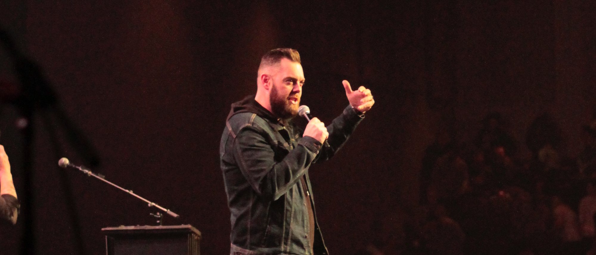 Drew Powell speaking on stage to a large audience